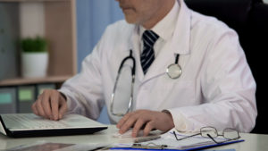 Doctor of medicine writing scientific article for magazine, working on laptop