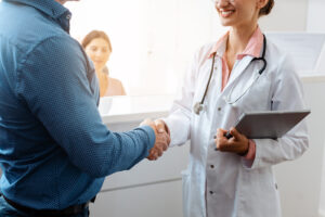 Doctor and patient shaking hands at front desk of doctor's office